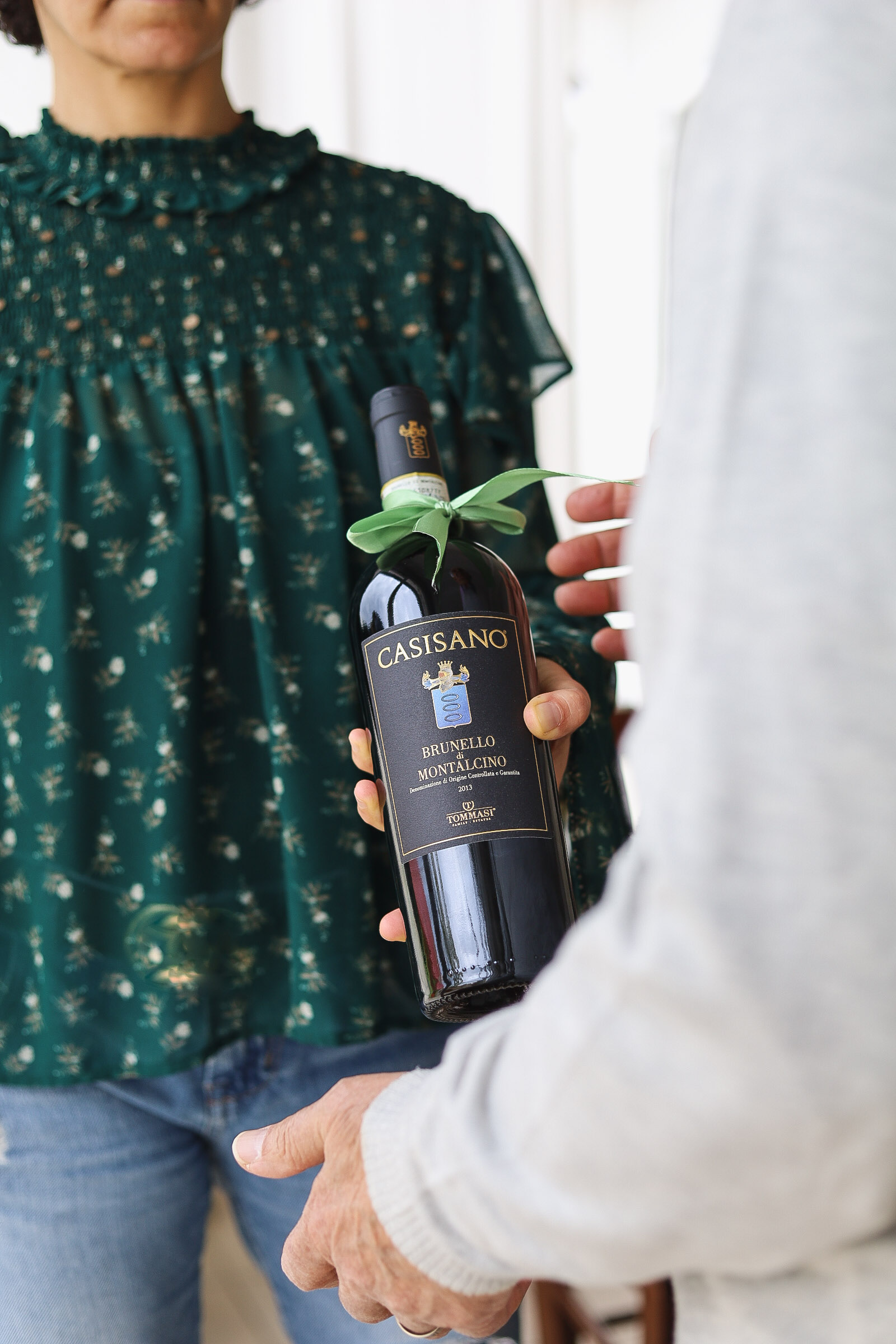 Frau überreicht Casisano Brunello Flasche mit Schleife an eine Person