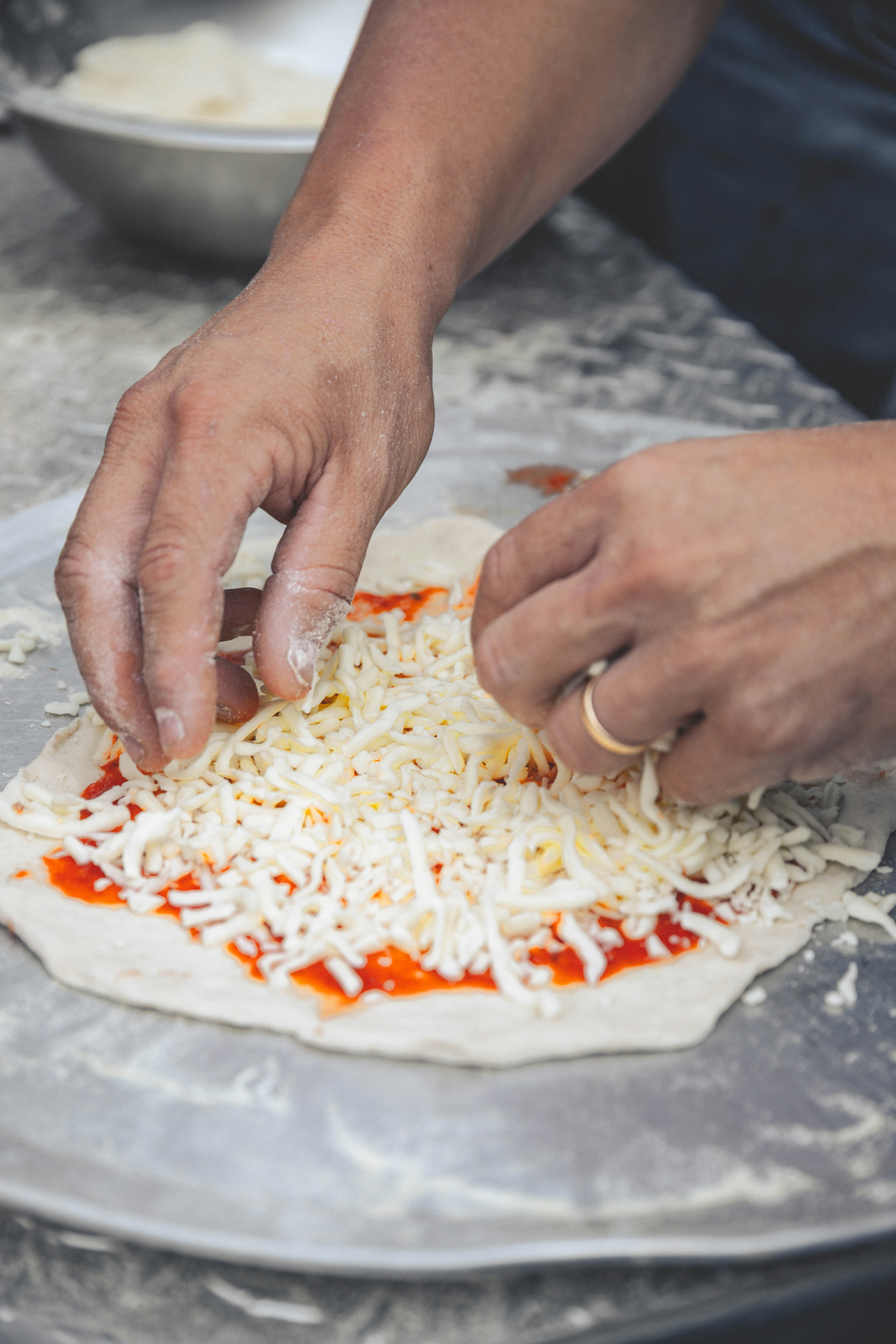 Pizzateig wird mit Käse belegt