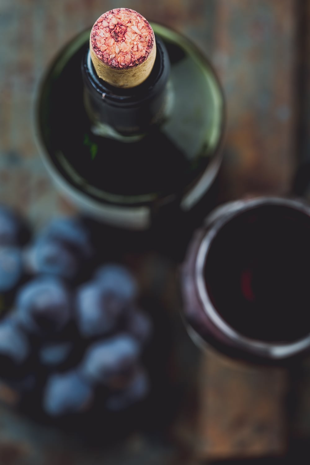 Rotweinflasche, Glas und Weintrauben auf Tisch