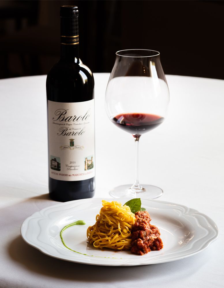 Pasta Ragú mit Glas Barolo auf Tisch